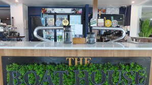 A bar area with a sign reading "THE BOATHOUSE" and various beer taps. - Mackay Seabreeze Apartments (Slade Point)
