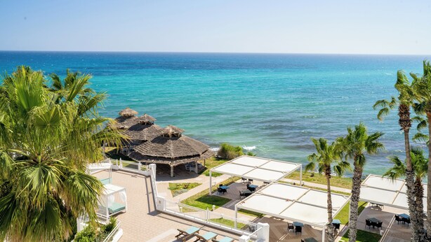 Um resort com área de piscina, espaço para sentar ao ar livre e vista para o oceano.