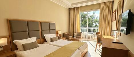 Habitación de hotel con dos camas, un balcón, un escritorio y un televisor.