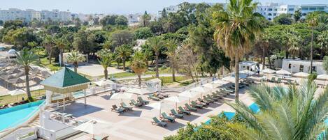 Un resort con piscina, tumbonas y palmeras.