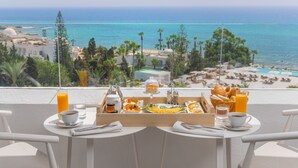 A breakfast table with a view of the ocean and beach, including a tray with bread, fruit, and coffee. - Royal Azur Thalassa (Hammamet)