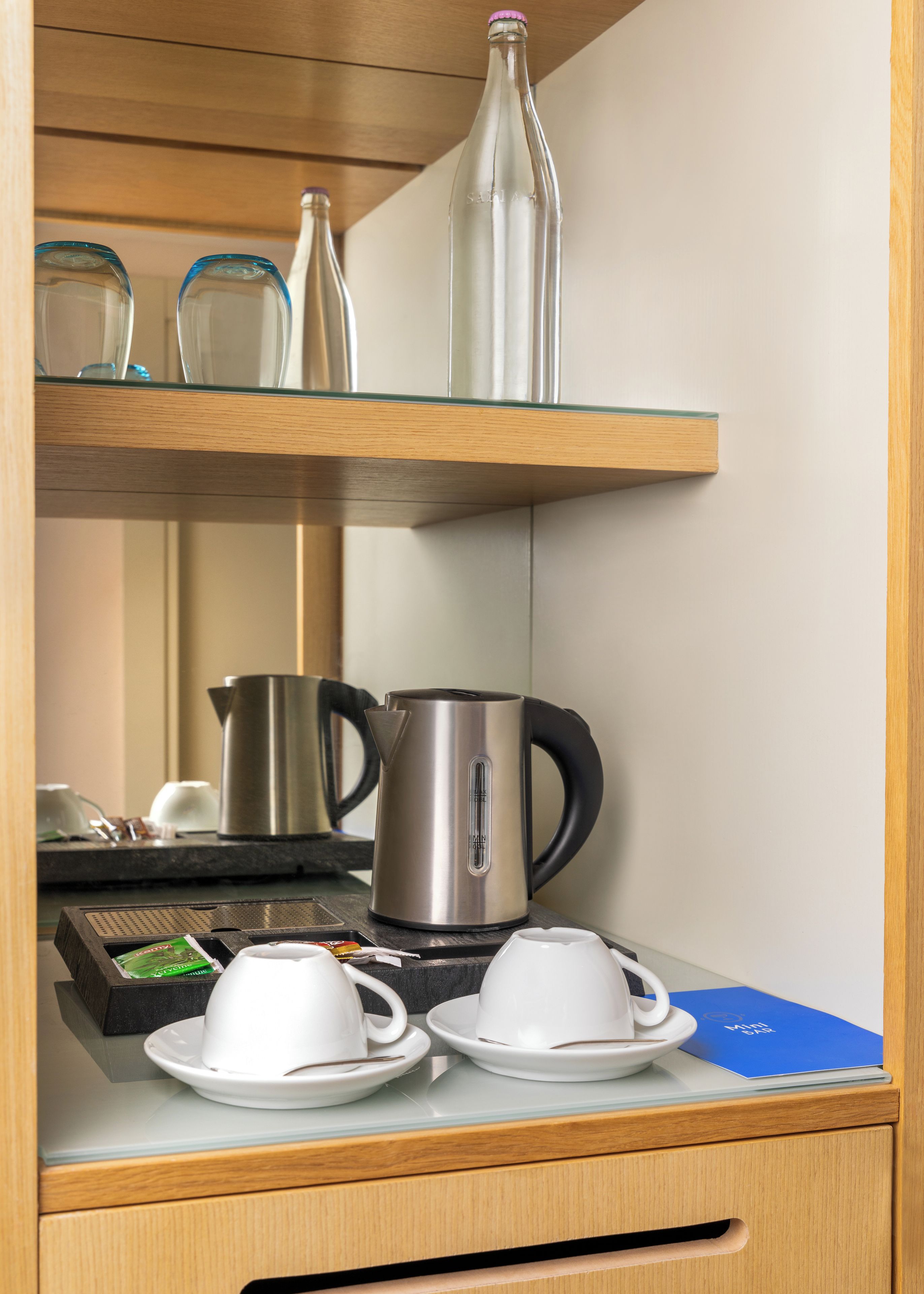 Eine Küchenzeile mit einer Kaffeemaschine, zwei Tassen und einem Wasserkocher auf einer Holzauslage.