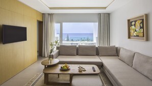 A modern living room with a sofa, a coffee table with fruits, a remote, and a painting on the wall. - Royal Azur Thalassa (Hammamet)