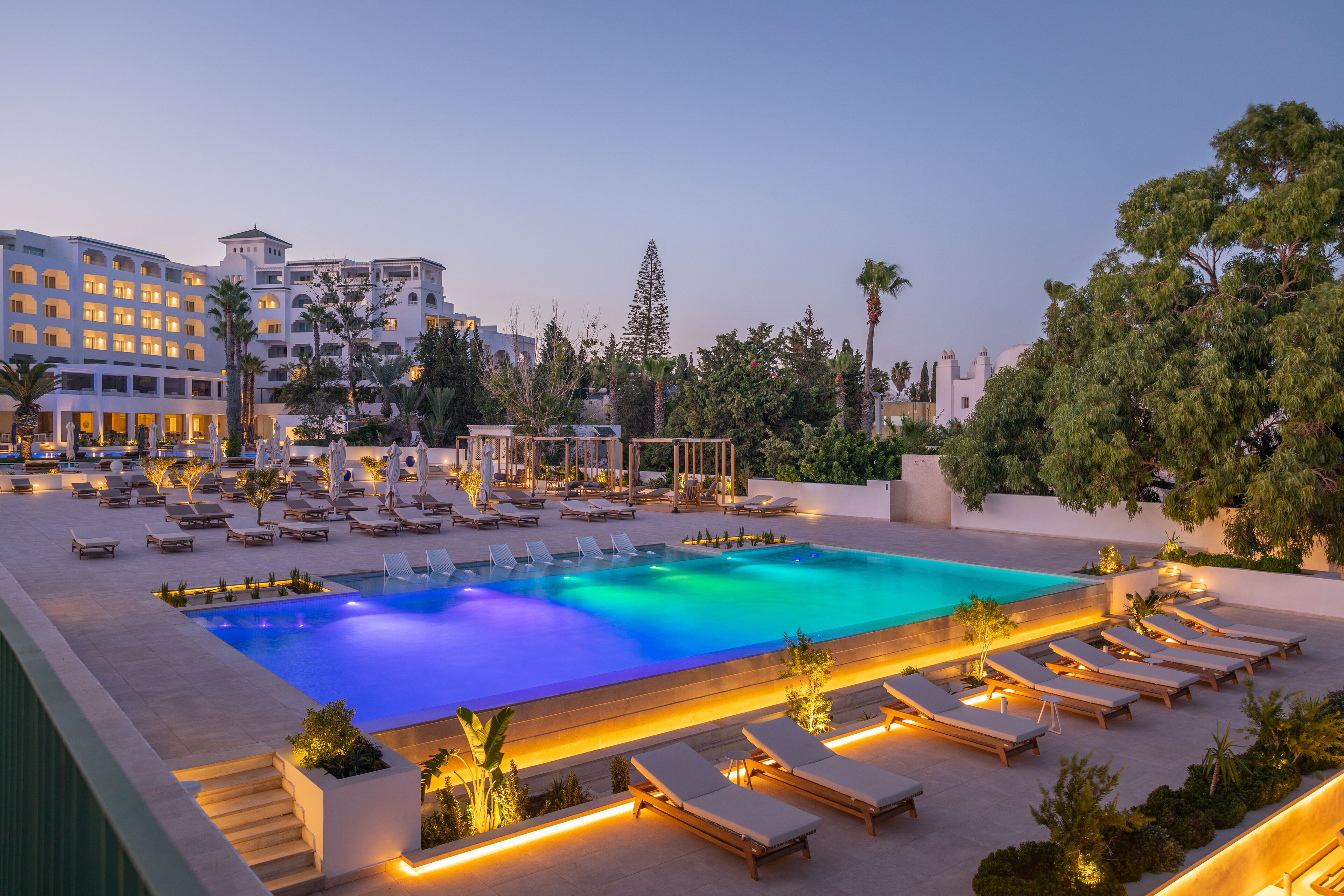 A hotel pool area with multiple lounge chairs and a large swimming pool.