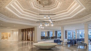 A spacious lobby with a large central fountain, intricate ceiling design, and modern seating areas. - Royal Azur Thalassa (Hammamet)