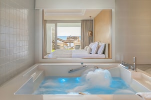 Un baño moderno con una bañera grande, ducha y vistas a un balcón con mesa y sillas.