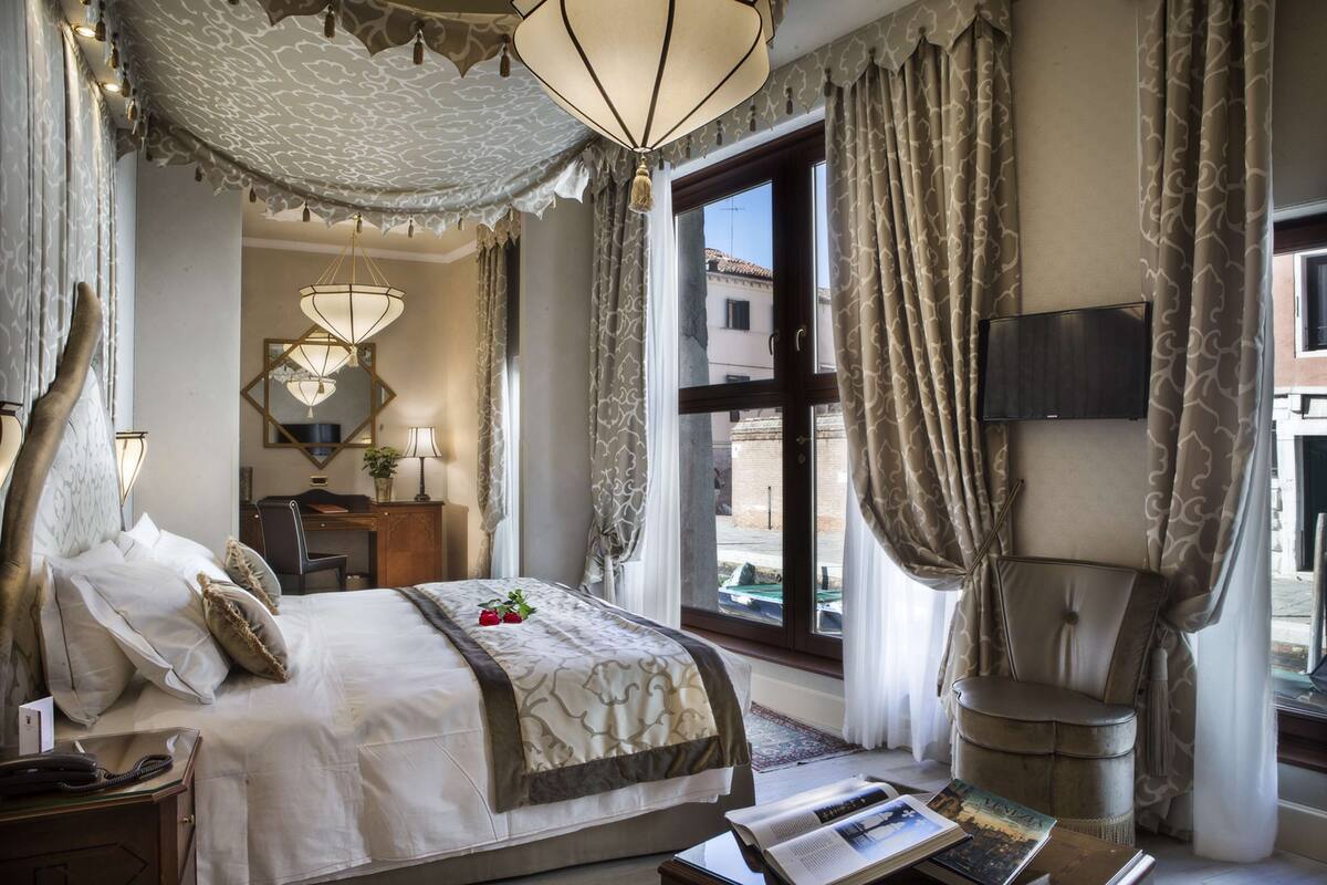 A well-appointed hotel room with a large bed, a desk, a chair, and a television.