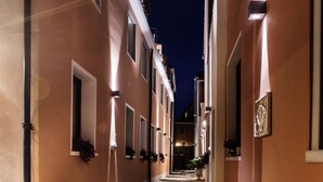 Un callejón estrecho flanqueado por edificios, iluminado por luces empotradas en la pared.