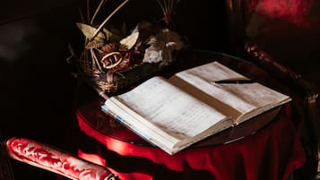An open book on a table with a red cloth, a pen, and decorative items including a basket and a wooden sculpture.