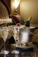 Two champagne flutes on a table with a metal bucket containing a bottle of champagne and ice cubes.