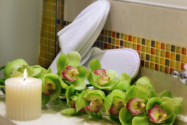 A bathroom with a white bathtub, a lit candle, and artificial green orchids. - Hotel ai Mori d'Oriente (Venice)