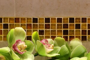 Primer plano de flores de orquídea con un revoque de azulejos al fondo.