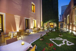 An outdoor dining area with tables and chairs, a well-maintained lawn, and a pathway leading to a building entrance.