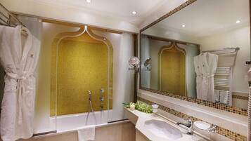 A bathroom with a bathtub, a sink, and a large mirror. There are towels hanging on a rack and a shower curtain.