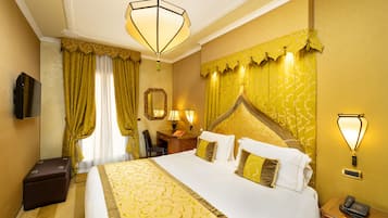 A hotel room with a large bed, a desk with a chair, a telephone, and a television.