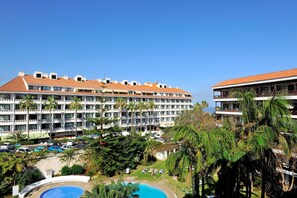 Un hôtel doté de nombreux balcons, d’une piscine et d’une végétation luxuriante.