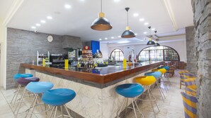 Un espace bar doté d’un comptoir en marbre, de plusieurs tabourets et d’un éclairage suspendu.