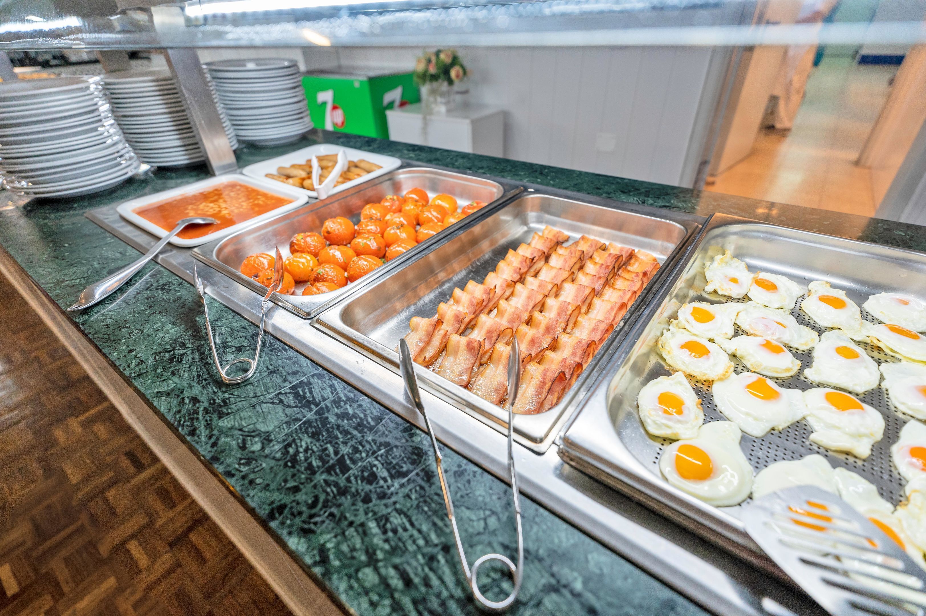 A buffet with various food options including eggs, bacon, and oranges.