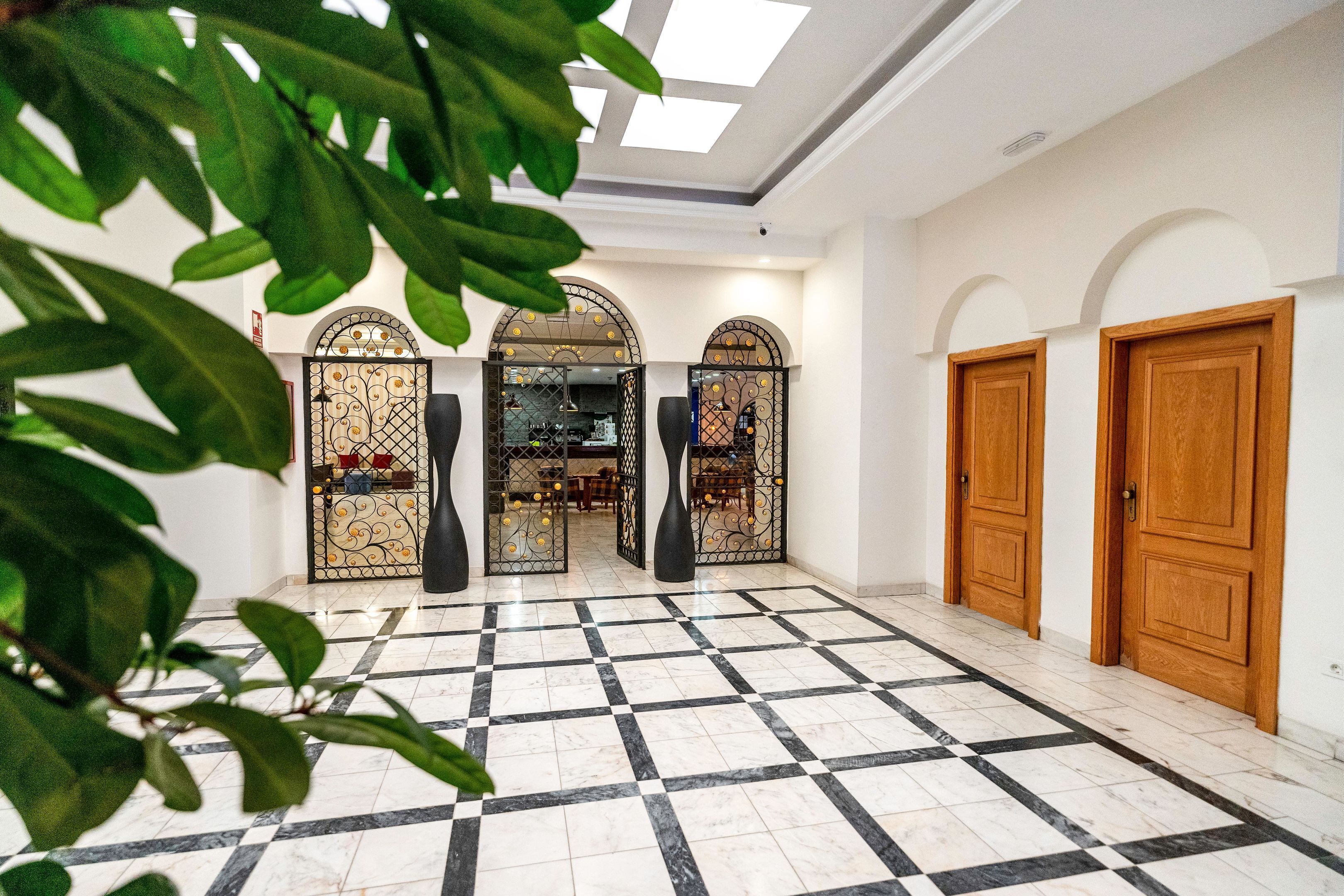 Un hall d’entrée avec un sol à carreaux, des portes en bois et un portail décoratif.