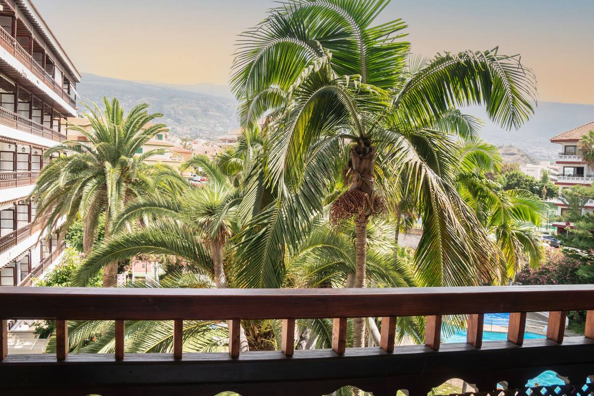 Een balkon met uitzicht op palmbomen en een uitgestrekte skyline.