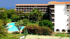 Un hôtel doté d’une piscine, d’une végétation luxuriante et offrant une vue sur la mer.