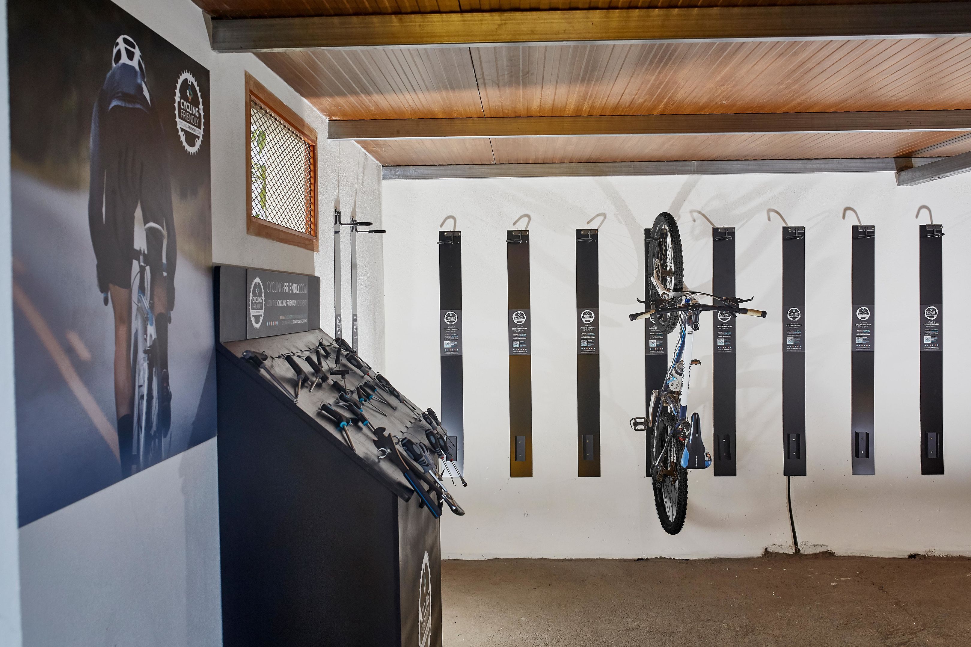 Una habitación con techo, una pared con ranuras verticales y una bicicleta colgada en la pared.