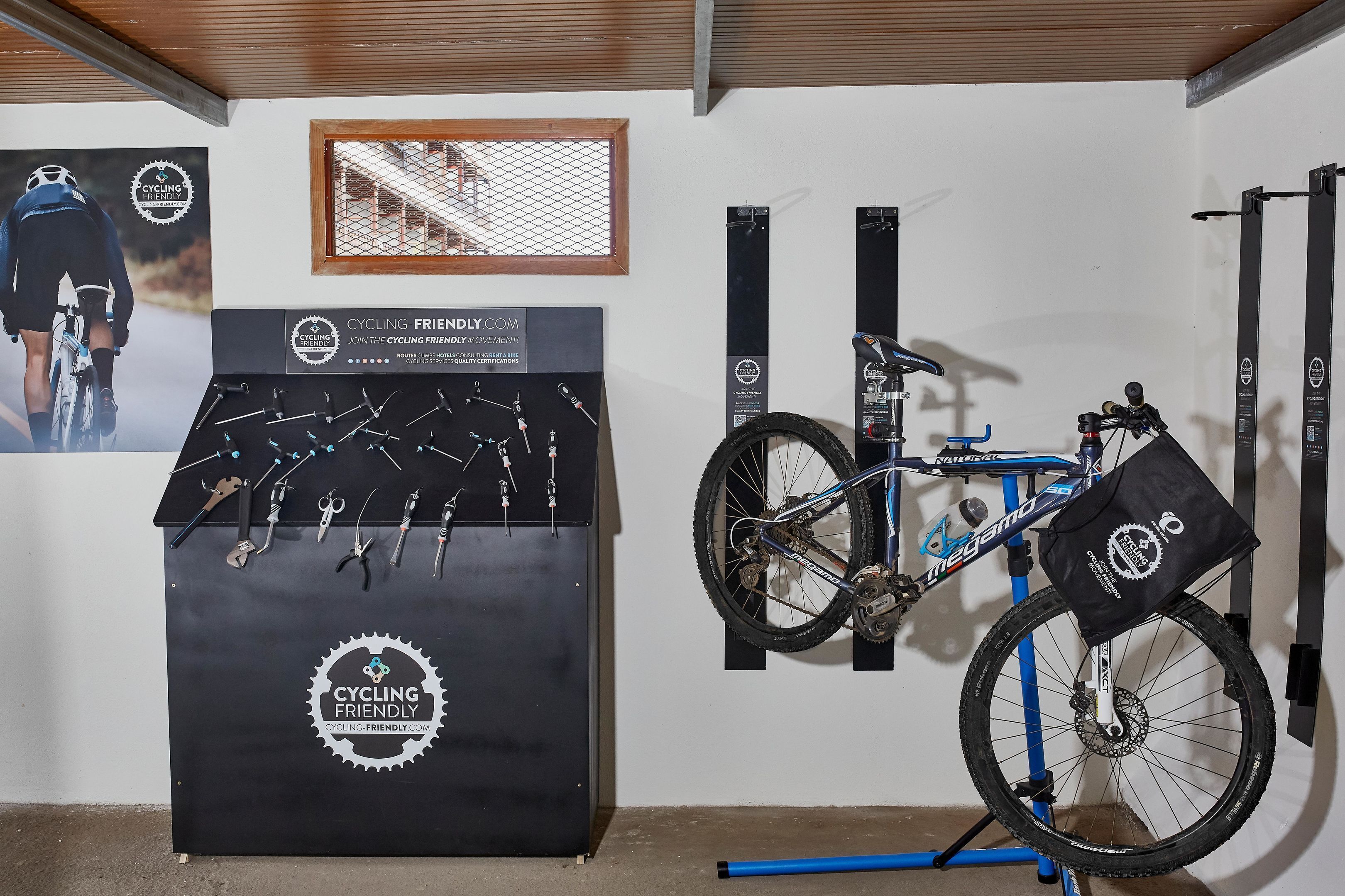 A room with a bicycle, a wall-mounted rack, and a poster.