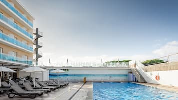 Een buitenzwembad, parasols bij het zwembad en ligstoelen