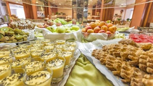A buffet with various food items including fruits, pastries, and beverages.