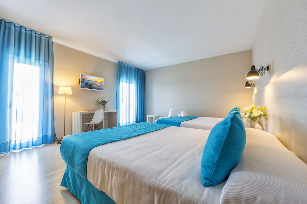 Habitación de hotel con dos camas, un escritorio y una silla.