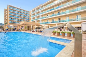 Een hotel met een zwembad, terras en een waterval.