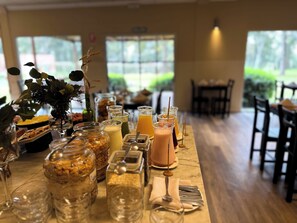 A dining area with a long table set with various drinks, food, and condiments. - Casa del Sol (Colonia del Sacramento)
