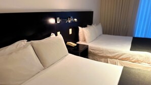 A hotel room with two beds, a nightstand, and a wall-mounted light fixture. - Casa del Sol (Colonia del Sacramento)