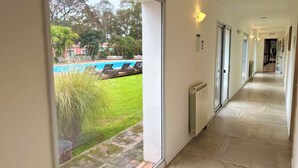 A hotel corridor with a view of a swimming pool and a grassy area. - Casa del Sol (Colonia del Sacramento)