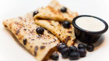 Crepas con arándanos y un tazón pequeño de crema.