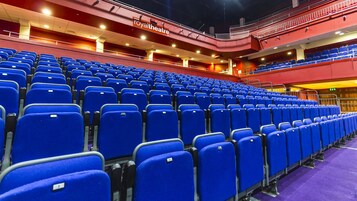 Un teatro vacío con asientos azules y una sección superior roja.