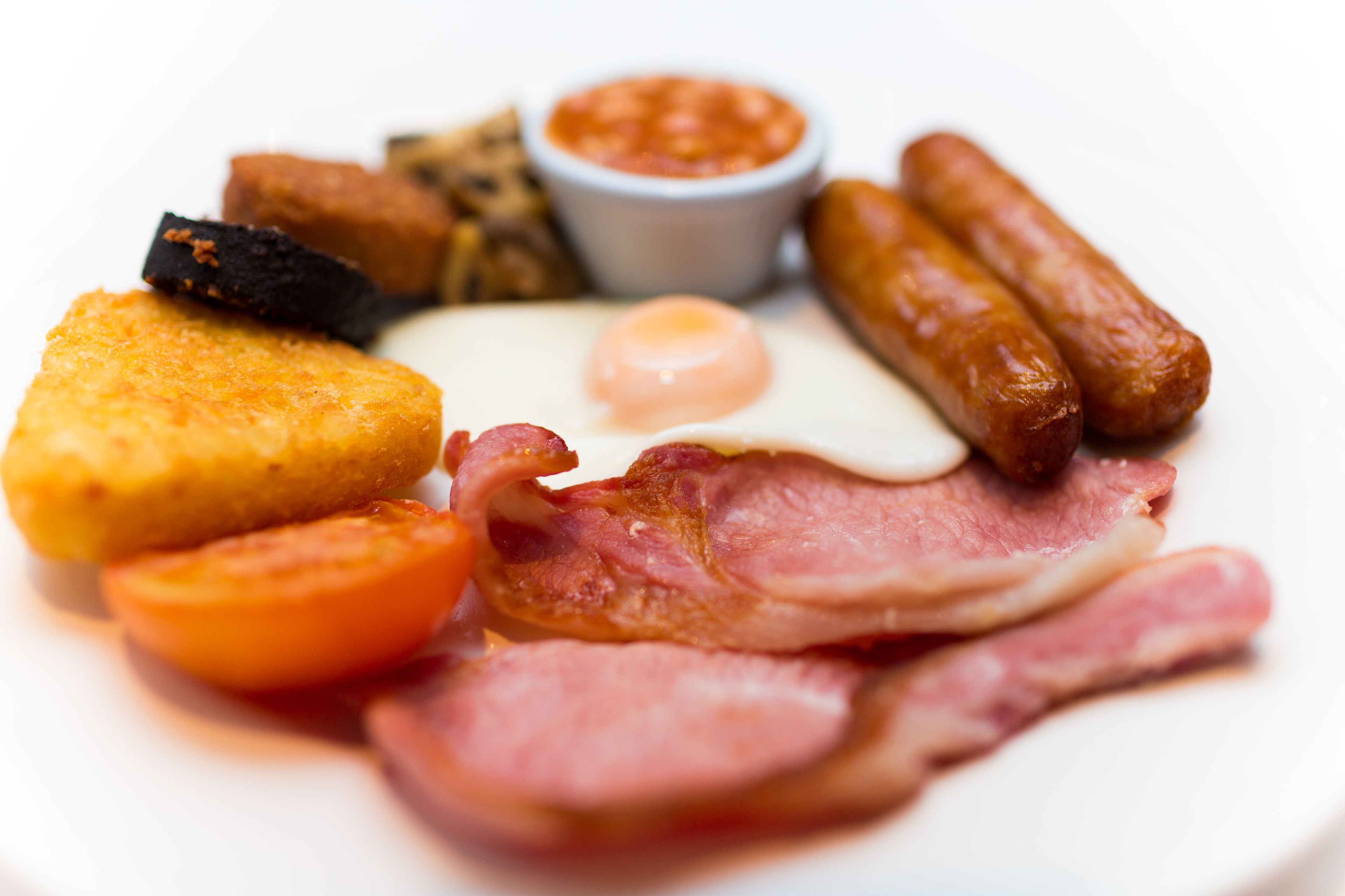 Ein Frühstücksteller mit Eiern, Würstchen, Speck, Toast und gebackenen Bohnen.