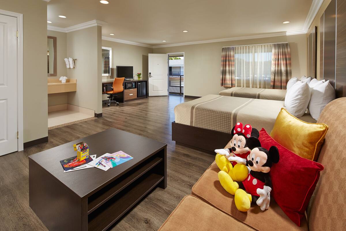 Une chambre d’hôtel avec un canapé, une table basse et des peluches à l’effigie de Mickey Mouse.