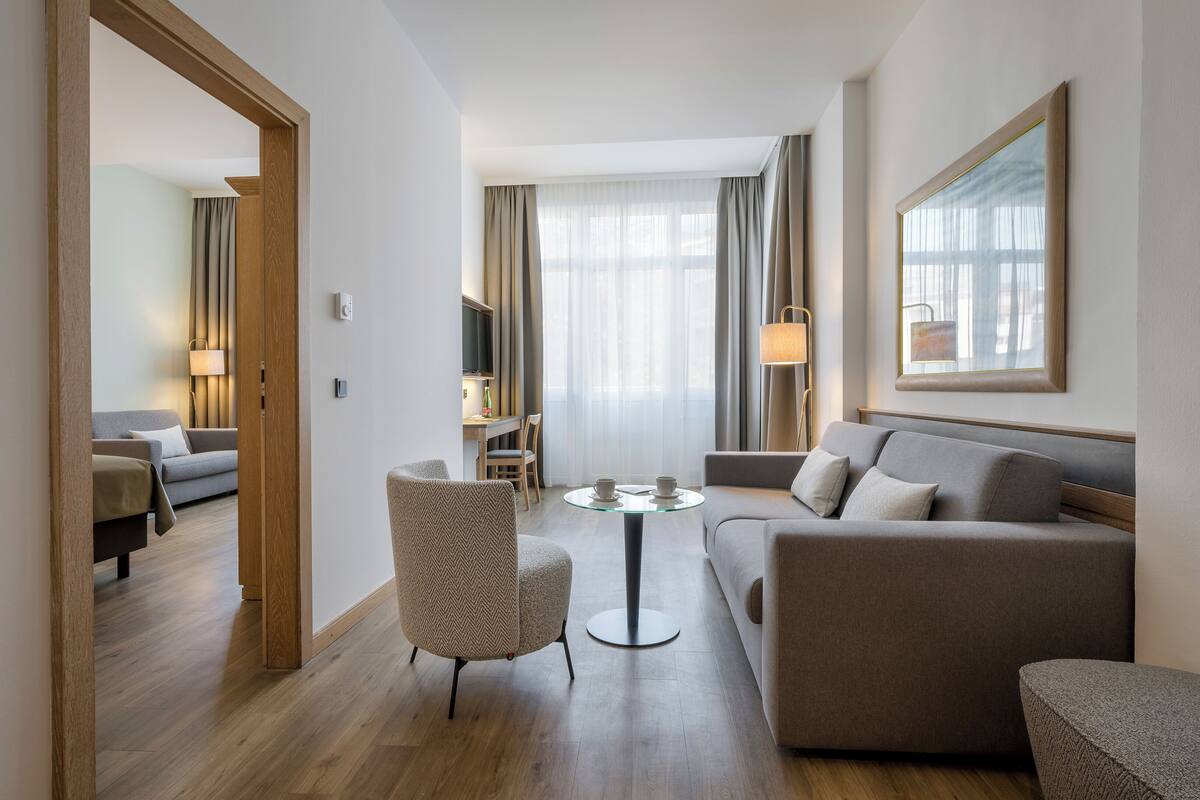 Habitació d'hotel moderna amb un sofà, una butaca i una taula rodona petita.