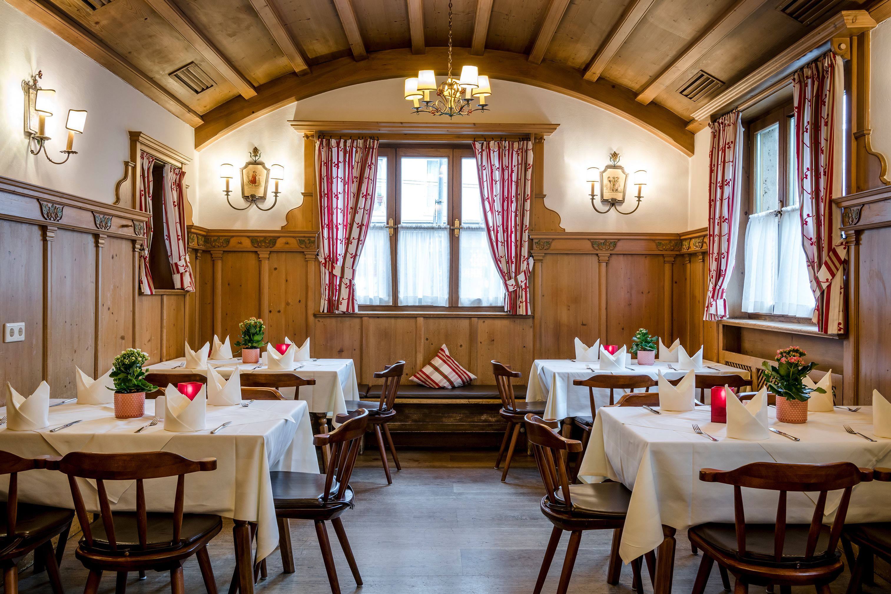 Un comedor con paredes de madera, candelabros y mesas dispuestas para una comida.