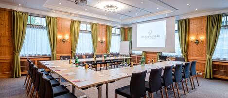 A conference room with a long table, chairs, a projector screen, and a presentation on the wall.