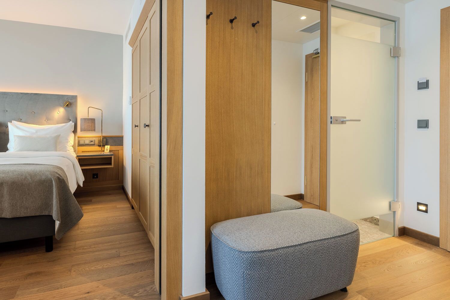 A bedroom with a bed, bedside tables, a wardrobe, and a small seating area.