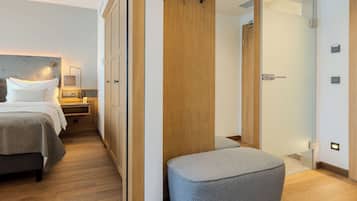 A bedroom with a bed, bedside tables, a wardrobe, and a small seating area.
