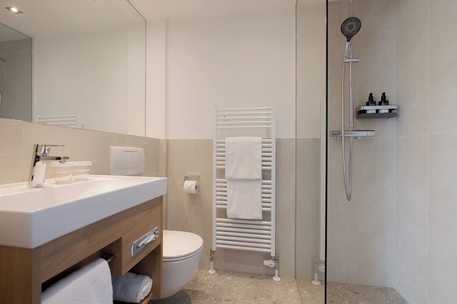 A modern bathroom with a white sink, toilet, and glass shower enclosure.