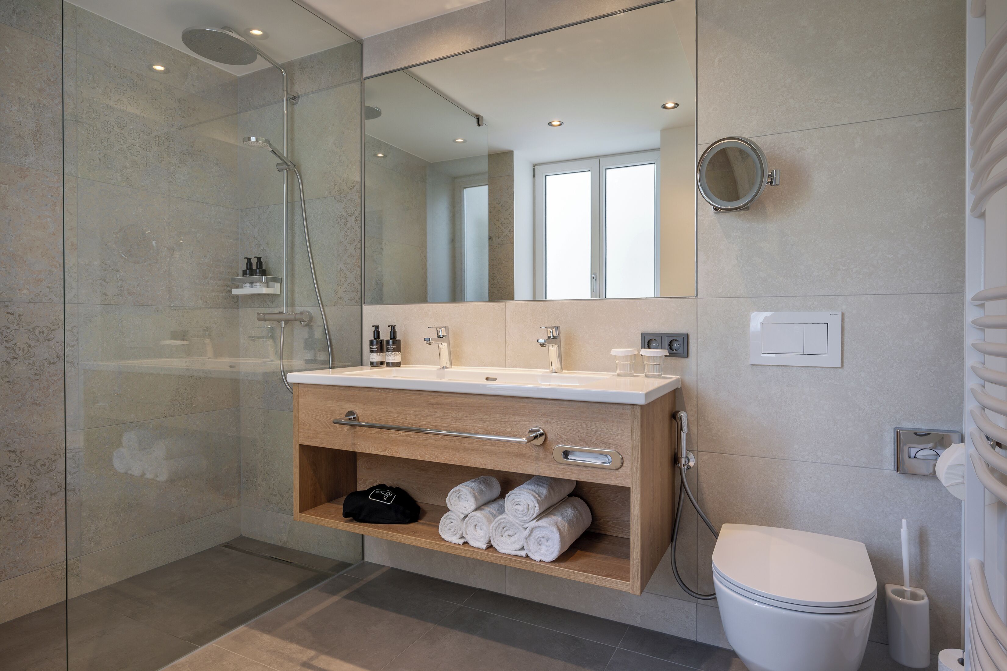 Un bagno moderno con doccia vetrata, mobile bagno in legno con specchio e servizi igienici.