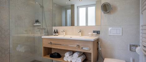 Un bagno moderno con doccia vetrata, mobile bagno in legno con specchio e servizi igienici.