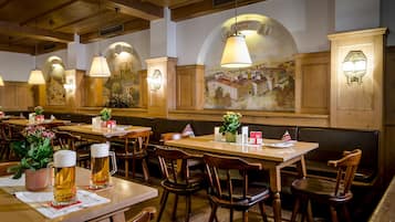 Un interior de restaurante con mesas y sillas de madera, y un mural en la pared.