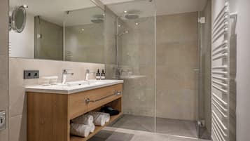 A modern bathroom with a wooden vanity, a glass shower enclosure, and a white towel rack.