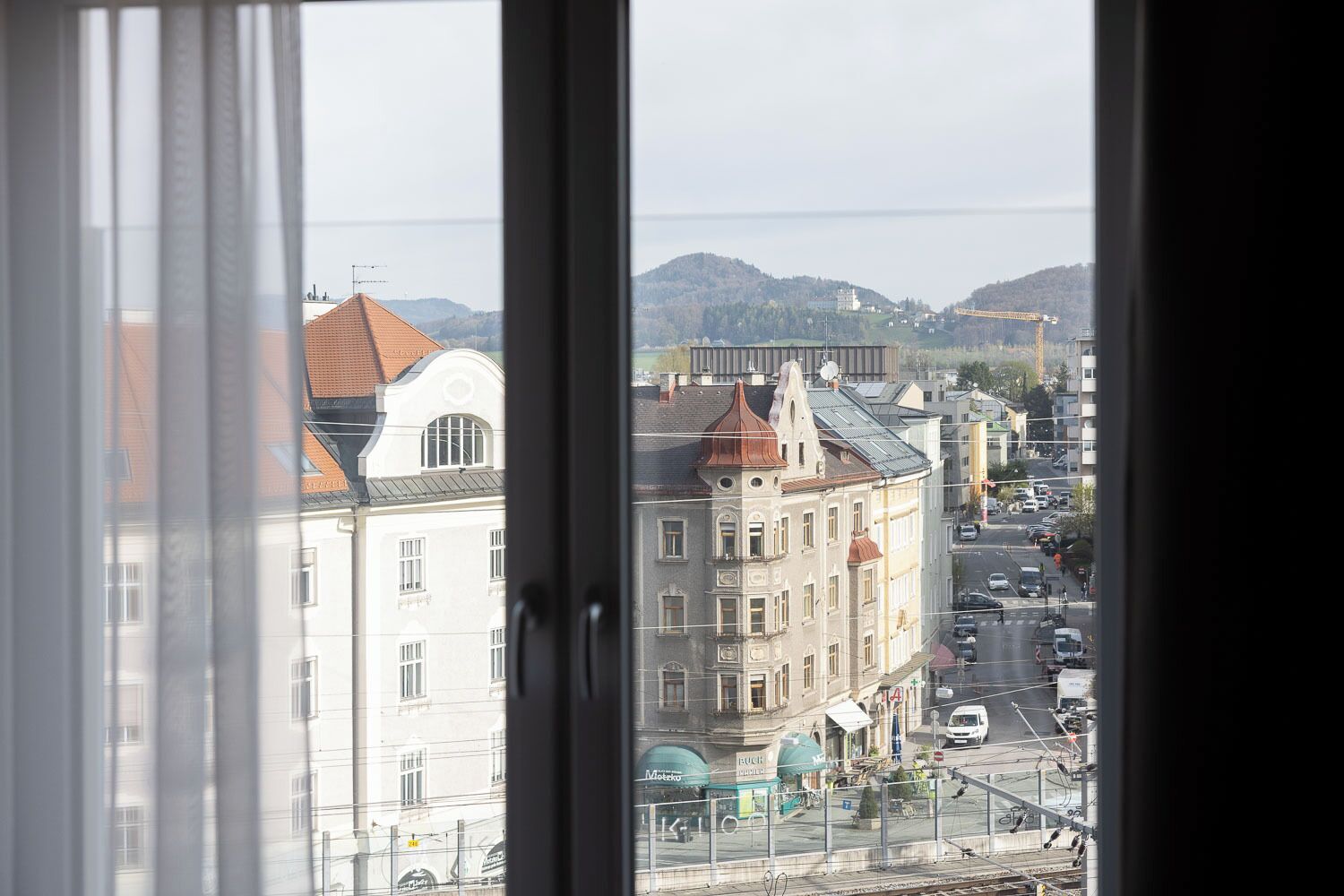 A view through a window of a cityscape with buildings, a bridge, and a road.