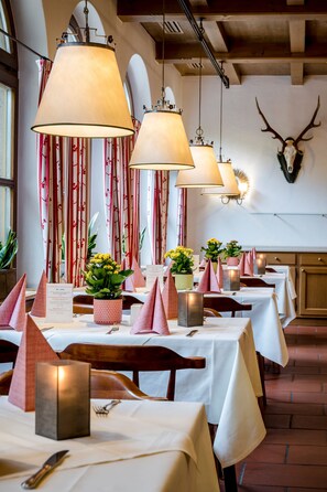 Un restaurante con mesas dispuestas para comer, con centros de mesa con velas y arreglos florales.